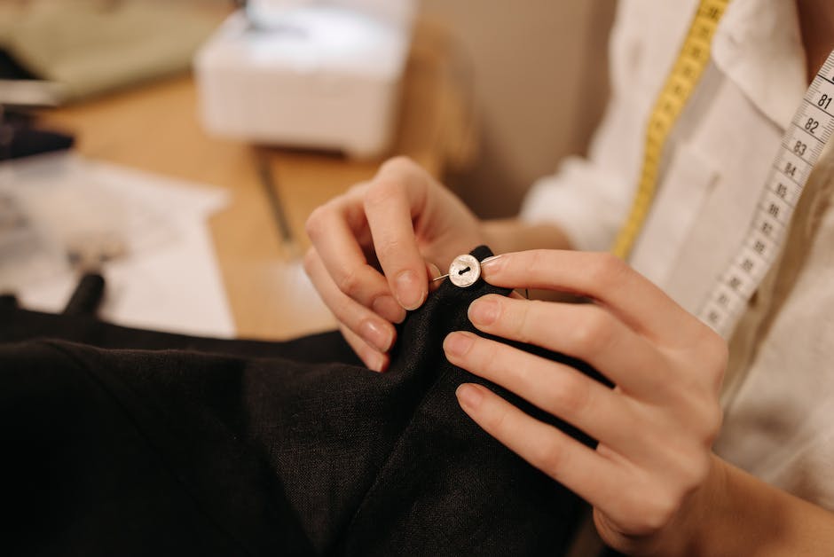 Image of a person sewing a button onto a shirt