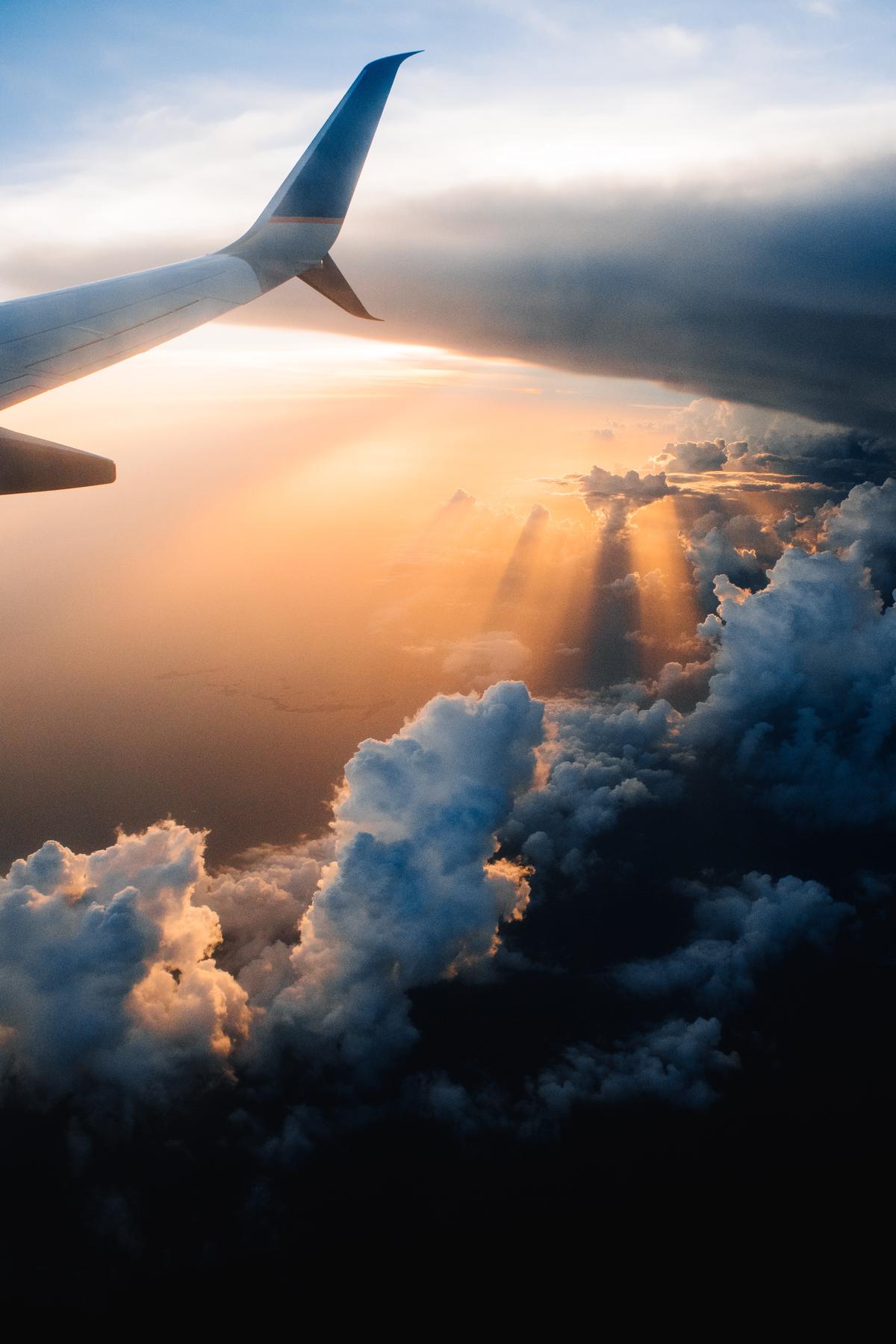 An image of a person holding a suitcase with a plane taking off in the background, representing travel and flight deals.